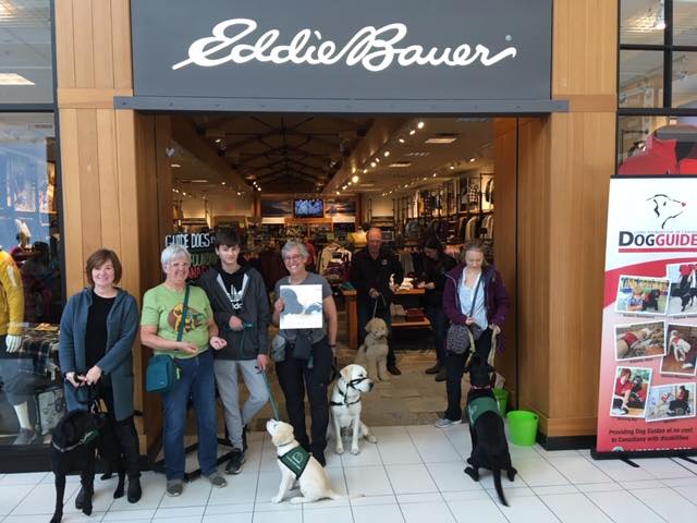 Six people and five service dogs selling calendars at Eddie Bauer